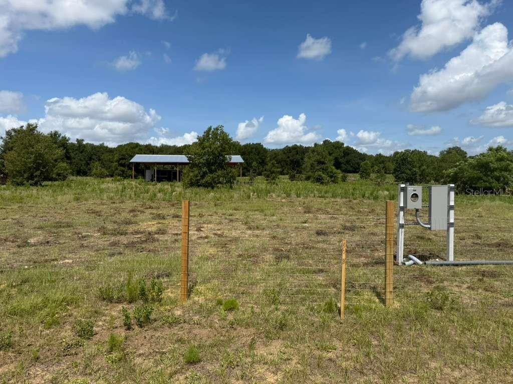 A fenced, grassy lot features a small open-sided structure and an electrical service panel — 22029 COUNTY ROAD 561, ASTATULA, FL