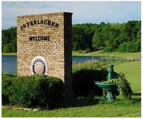 A brick welcome sign for Interlachen stands near a green lawn, a fountain, and a lake — 175 PARK AVENUE, INTERLACHEN, FL