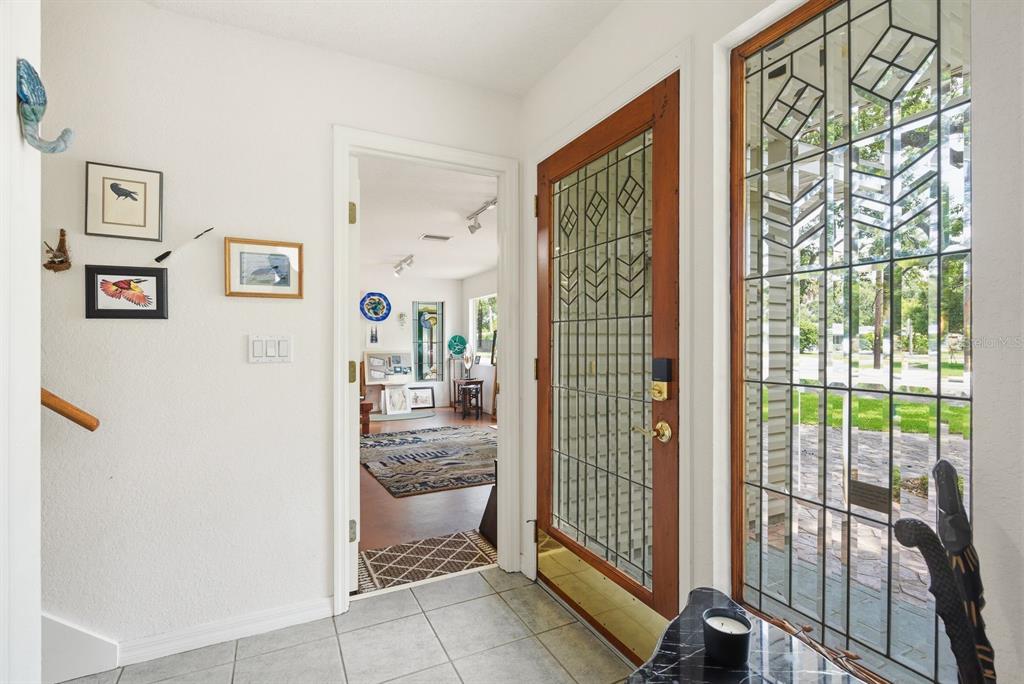 A two-story house with light green siding and a paved driveway under large oak trees — 755 SAN CHRISTOPHER DRIVE, DUNEDIN, FL