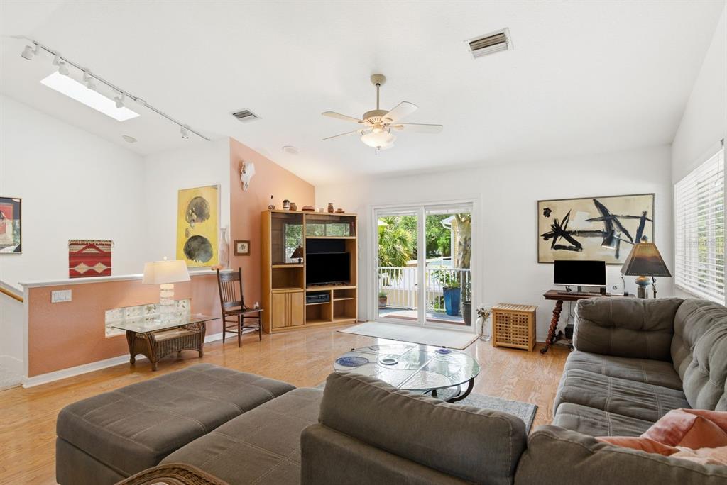 A living room with light wood floors, a ceiling fan, and an open kitchen area — 755 SAN CHRISTOPHER DRIVE, DUNEDIN, FL