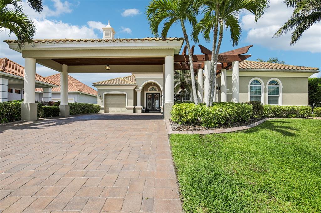 A paved driveway leads to a covered entryway with a pergola and palm trees — 4741 MAINSAIL DRIVE, BRADENTON, FL