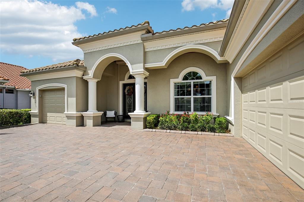 The exterior of a house features a paved driveway, a covered entryway, and two garages — 4741 MAINSAIL DRIVE, BRADENTON, FL