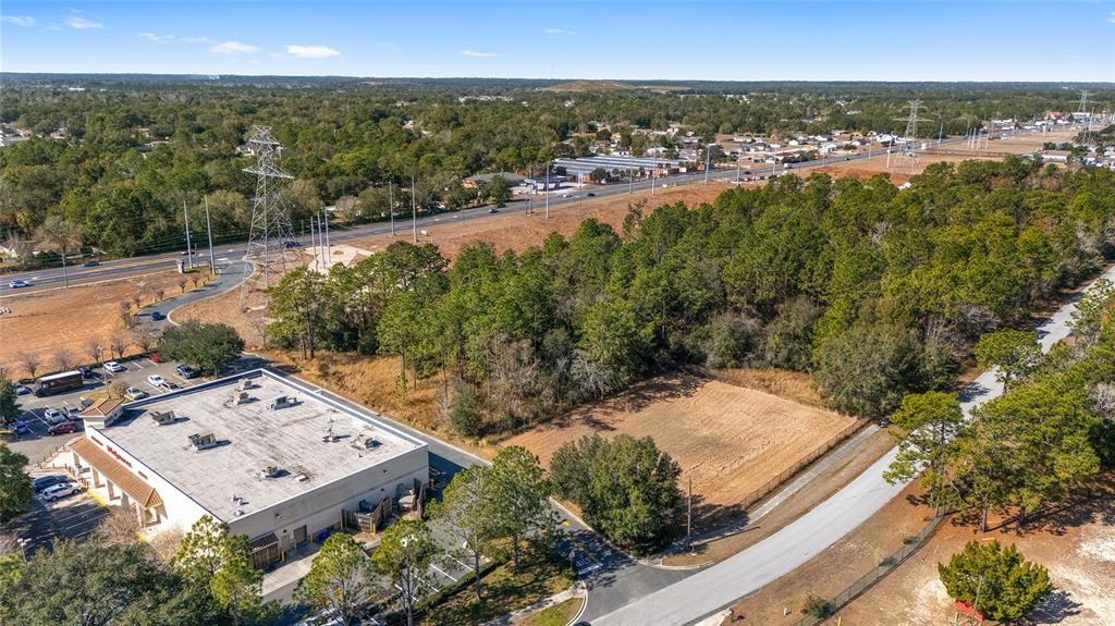 An aerial view shows a commercial building, a vacant lot, and a nearby highway — MARICAMP ROAD, OCALA, FL