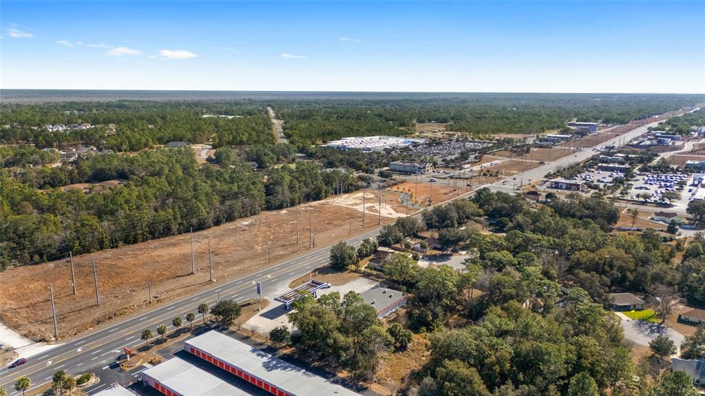 An aerial view shows a highway running through a wooded area with commercial buildings nearby — MARICAMP ROAD, OCALA, FL