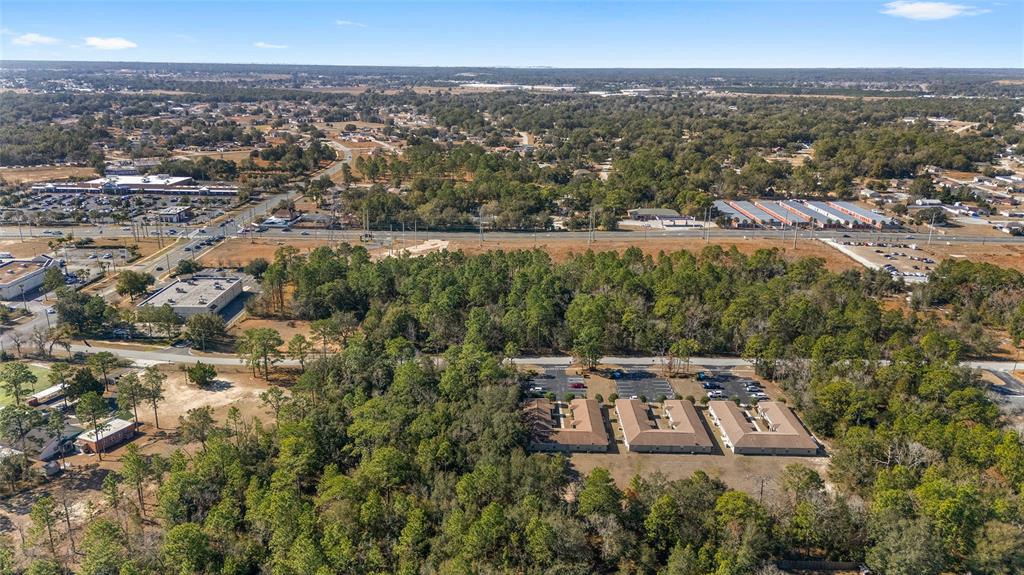 An aerial view shows a commercial building complex surrounded by dense trees and nearby roads — MARICAMP ROAD, OCALA, FL
