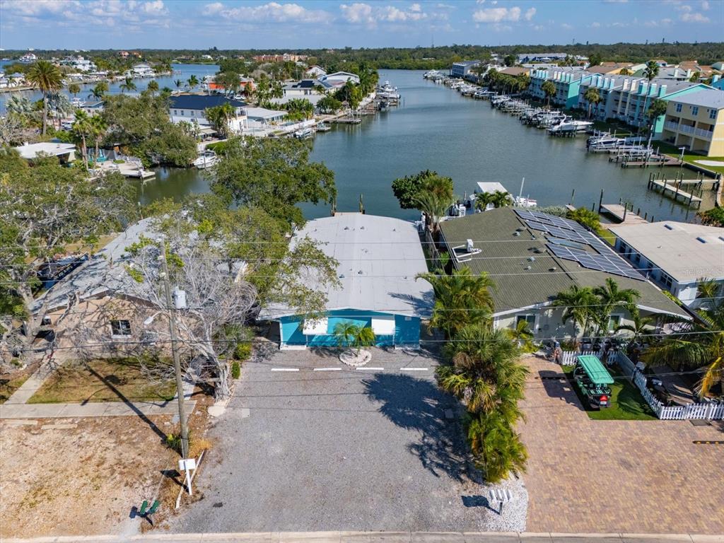 An aerial view shows a blue house with a gravel driveway situated on a canal — 711 E GULF BOULEVARD, INDIAN ROCKS BEACH, FL