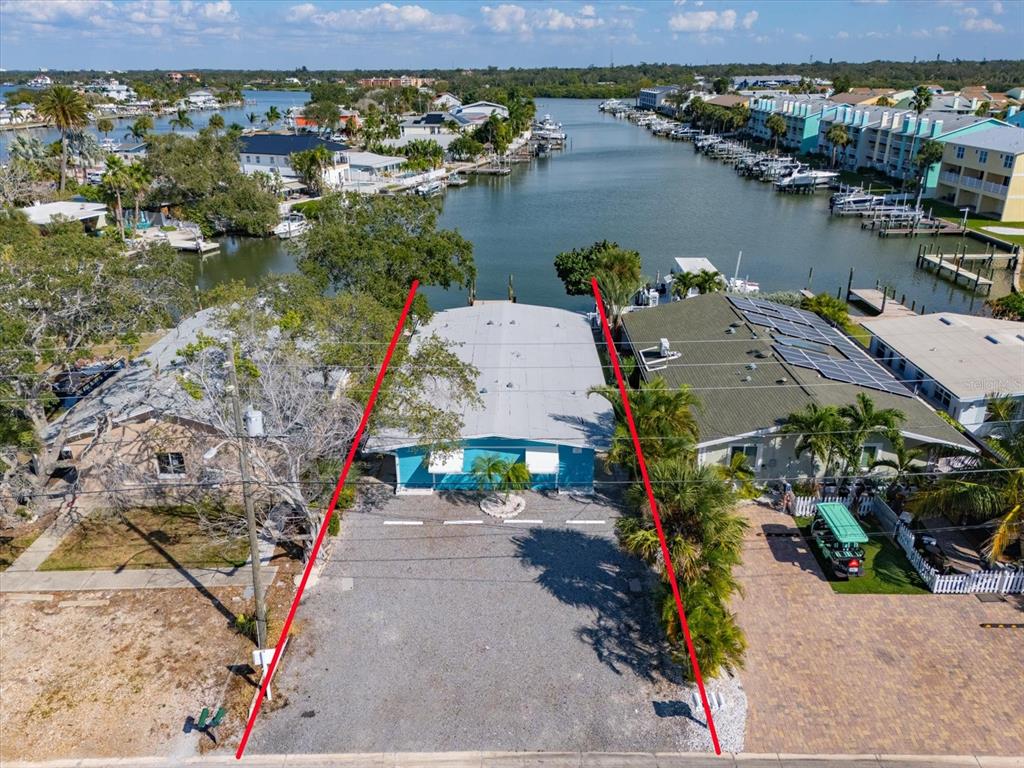 An aerial view shows a waterfront property with a gravel driveway and a blue house — 711 E GULF BOULEVARD, INDIAN ROCKS BEACH, FL