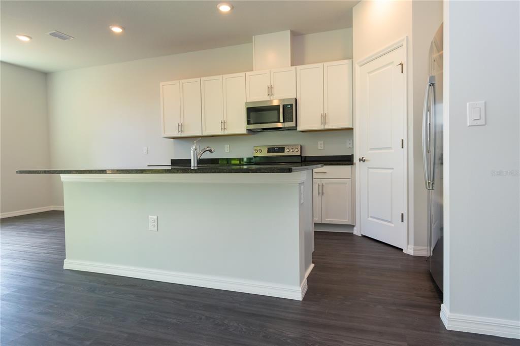 A kitchen features white cabinets, dark countertops, a kitchen island, and stainless steel appliances — 1348 PALAU STREET SE, PALM BAY, FL