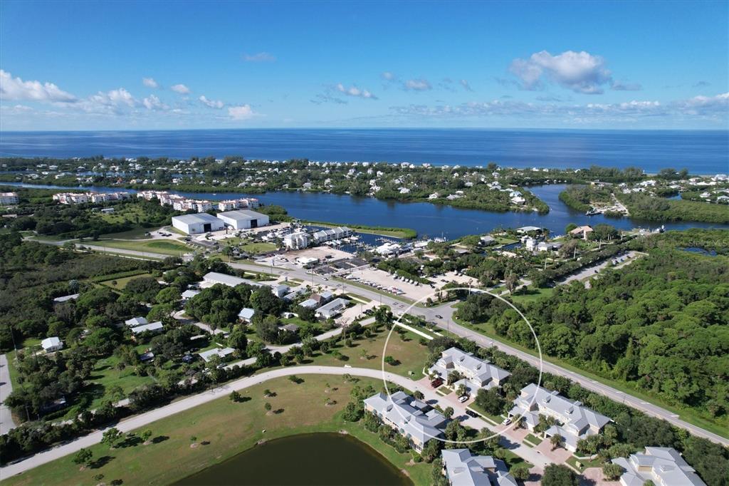 An aerial view shows a coastal residential area with a circled building near a road — 10640 LEMON CREEK LOOP UNIT 101, ENGLEWOOD, FL
