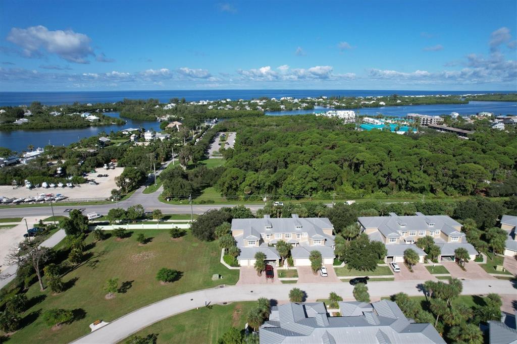 An aerial view shows a residential complex with townhomes, a parking lot, and surrounding greenery — 10640 LEMON CREEK LOOP UNIT 101, ENGLEWOOD, FL