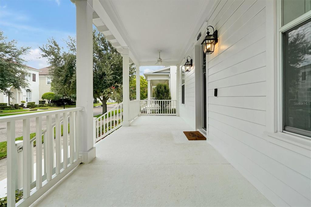 A white covered porch features a railing, ceiling fan, and two wall-mounted lanterns — 4036 HAWS LANE, ORLANDO, FL