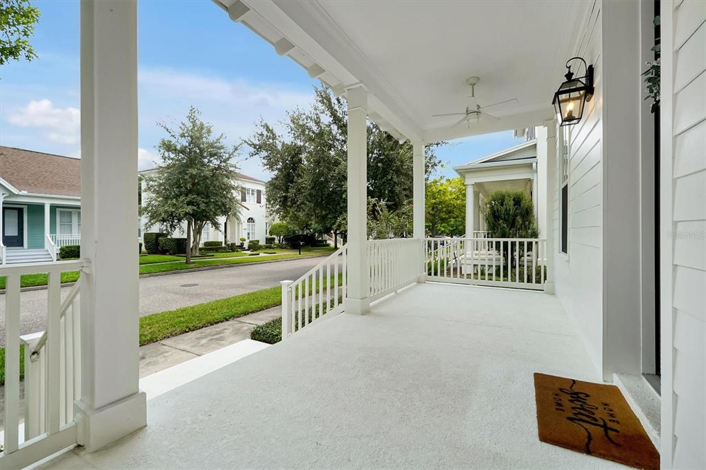 A white covered front porch with a railing, ceiling fan, and a welcome mat — 4036 HAWS LANE, ORLANDO, FL