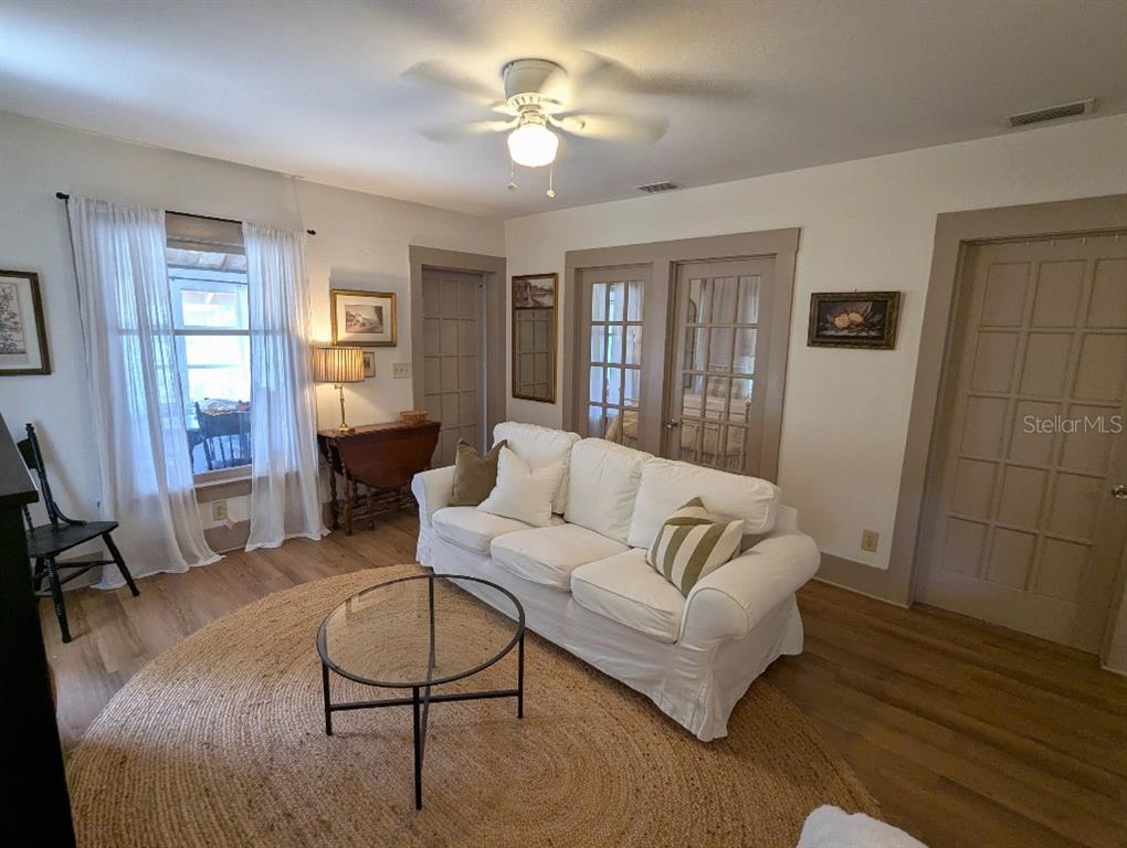 A living room features a white sofa, a round rug, and glass-paned doors — 7427 CHAPEL AVENUE, NEW PORT RICHEY, FL