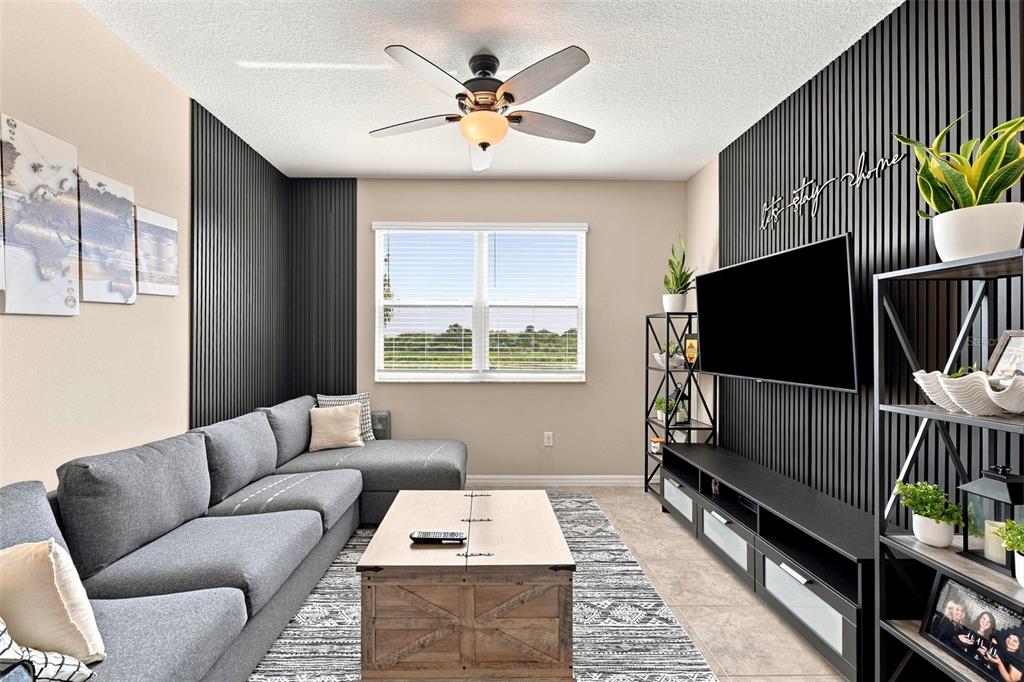 A living room features a gray sectional sofa, a wooden coffee table, and black slat walls — 15548 FLORENCE HOLLOW PLACE, SUN CITY CENTER, FL