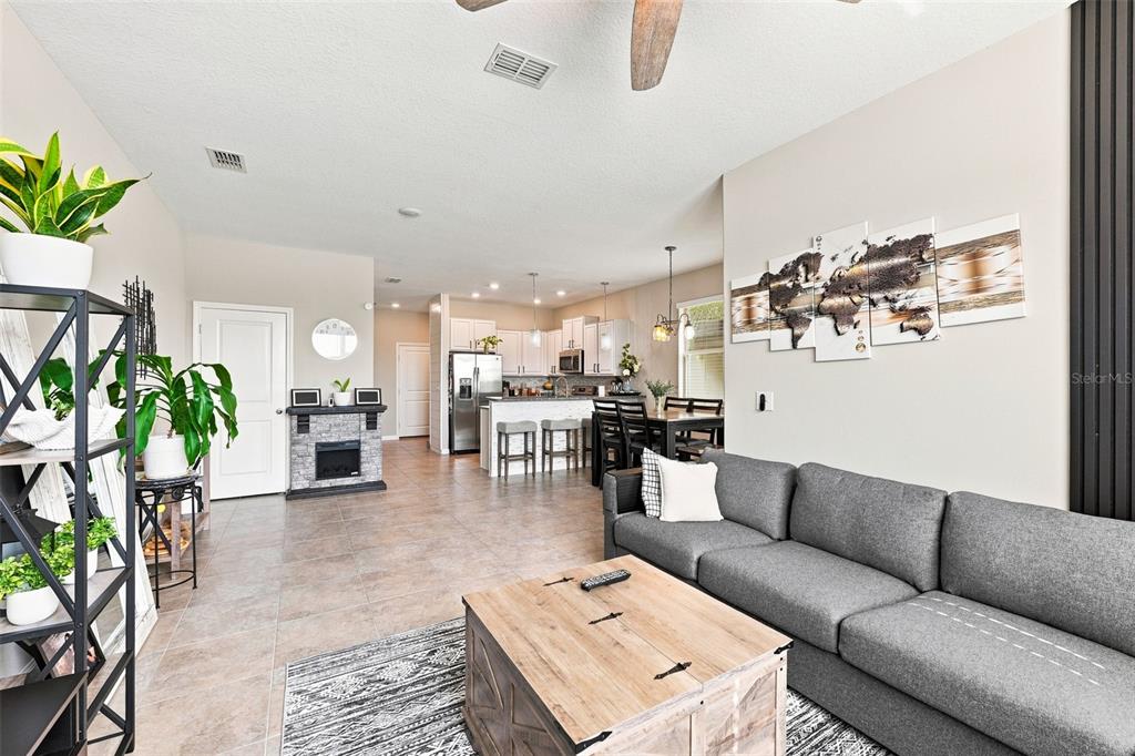A living room with a gray sofa, wood coffee table, and an open kitchen beyond — 15548 FLORENCE HOLLOW PLACE, SUN CITY CENTER, FL