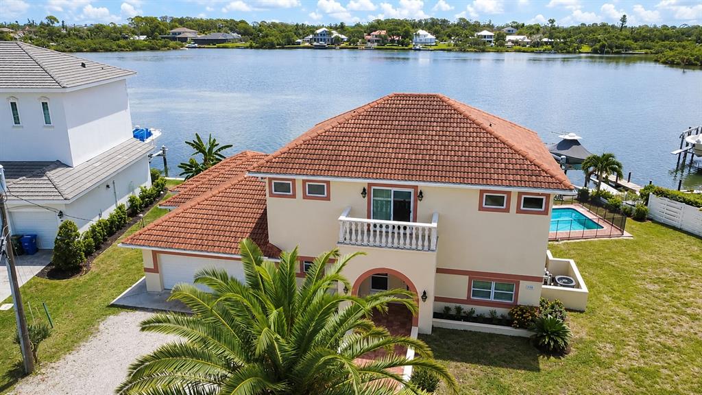 An aerial view shows a two-story house with a tiled roof, pool, and waterfront access — 919 KEY WAY, NOKOMIS, FL