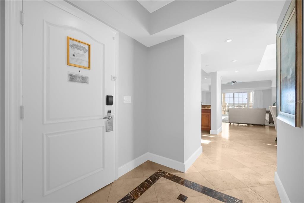 An entryway with a white door, tile flooring, and a view into a bright living area — 7593 GATHERING DRIVE UNIT 608, REUNION, FL
