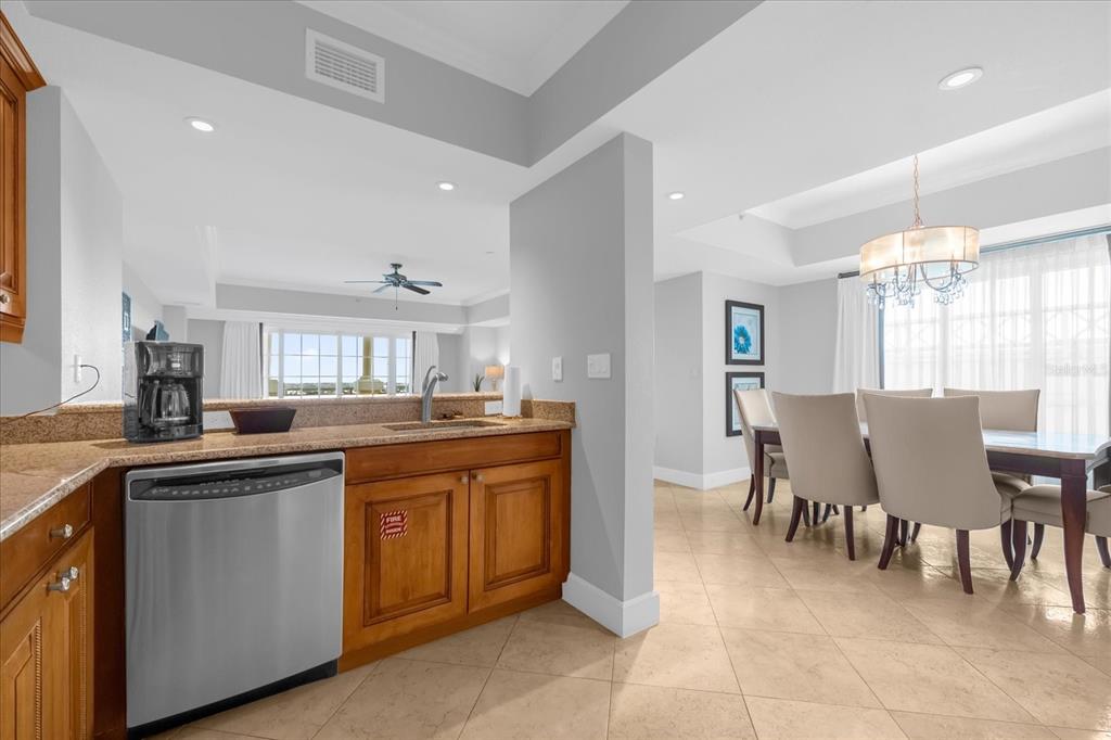 A kitchen with wood cabinets and stainless steel appliances overlooks a dining area with chairs — 7593 GATHERING DRIVE UNIT 608, REUNION, FL