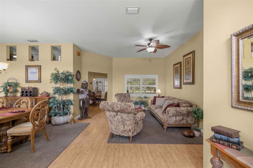 A living and dining area features light wood flooring, tan walls, and a ceiling fan — 5592 NE 61ST AVENUE ROAD, SILVER SPRINGS, FL