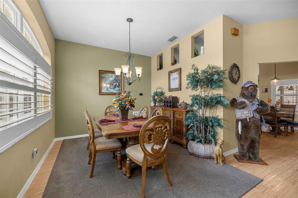 A dining room features a wooden table, chairs, a rug, and a decorative bear statue — 5592 NE 61ST AVENUE ROAD, SILVER SPRINGS, FL