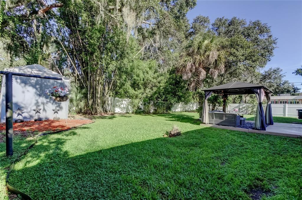 A backyard features a grassy lawn, a gazebo with patio furniture, and a storage shed — 375 10TH AVENUE N, SAFETY HARBOR, FL