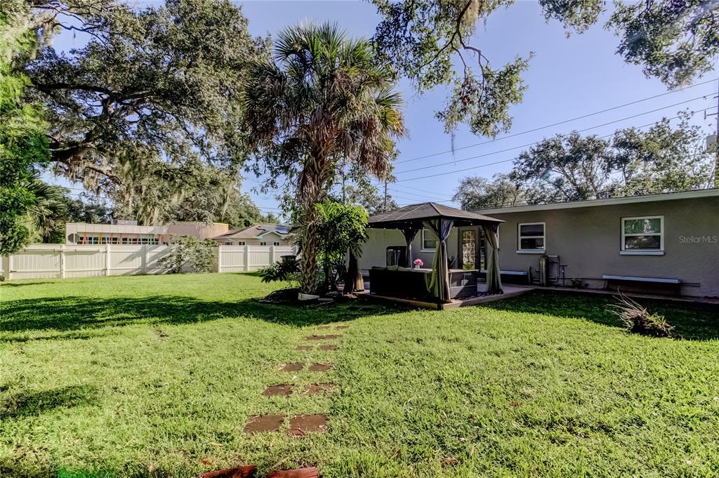 A backyard features a grassy lawn, a palm tree, a gazebo, and a white fence — 375 10TH AVENUE N, SAFETY HARBOR, FL