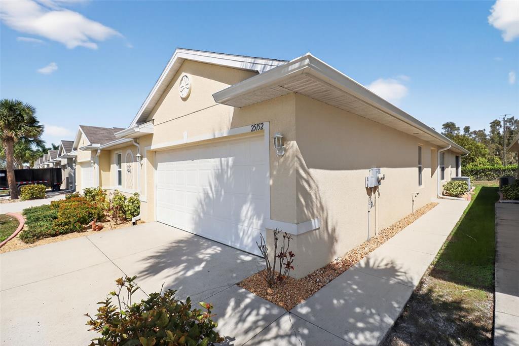 A beige single-story house with a white garage door and a concrete driveway — 25152 E LENOX CIRCLE, PUNTA GORDA, FL