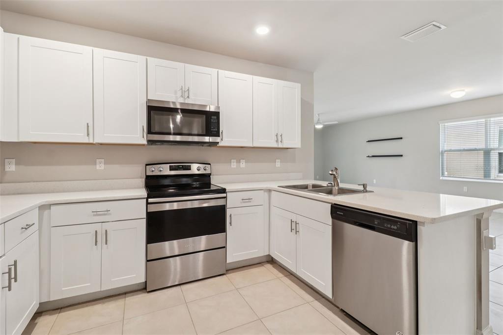 A kitchen with white cabinets, stainless steel appliances, and light-colored countertops — 25152 E LENOX CIRCLE, PUNTA GORDA, FL