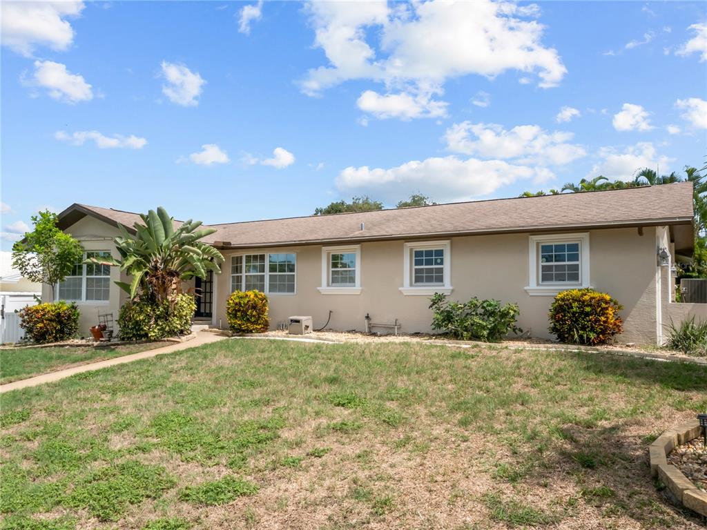 A single-story house with a tan exterior, a brown roof, and a front lawn — 14331 APACHE AVENUE, LARGO, FL