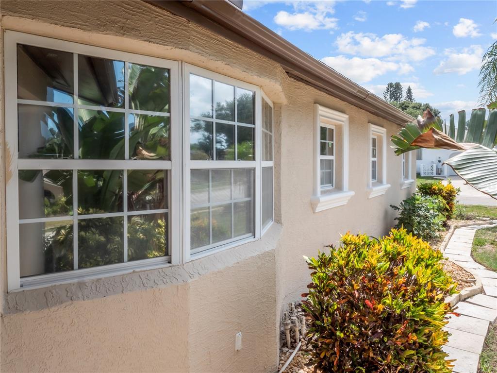 The exterior of a beige stucco house features a bay window and two smaller windows — 14331 APACHE AVENUE, LARGO, FL
