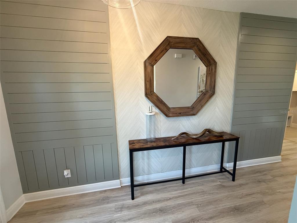 An entryway features a console table, an octagonal mirror, and walls with gray shiplap paneling — 1656 HAMLIN RIDGE ROAD, MINNEOLA, FL