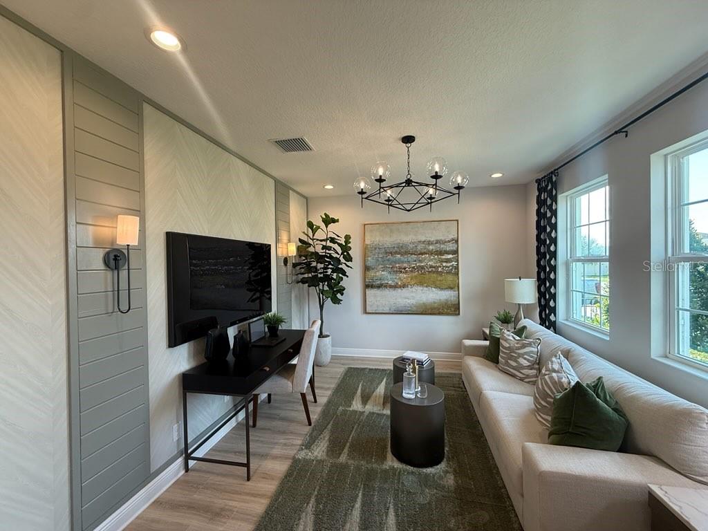 A home office with a desk, sofa, patterned accent wall, and a modern chandelier — 1656 HAMLIN RIDGE ROAD, MINNEOLA, FL
