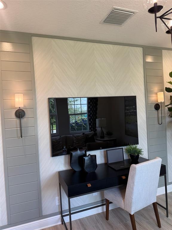A home office features a desk, a wall-mounted television, and sage green shiplap accent walls — 1656 HAMLIN RIDGE ROAD, MINNEOLA, FL