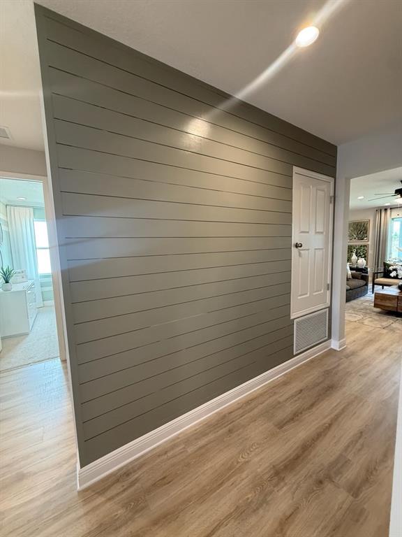 A hallway features a gray shiplap accent wall with a built-in door and floor vent — 1656 HAMLIN RIDGE ROAD, MINNEOLA, FL