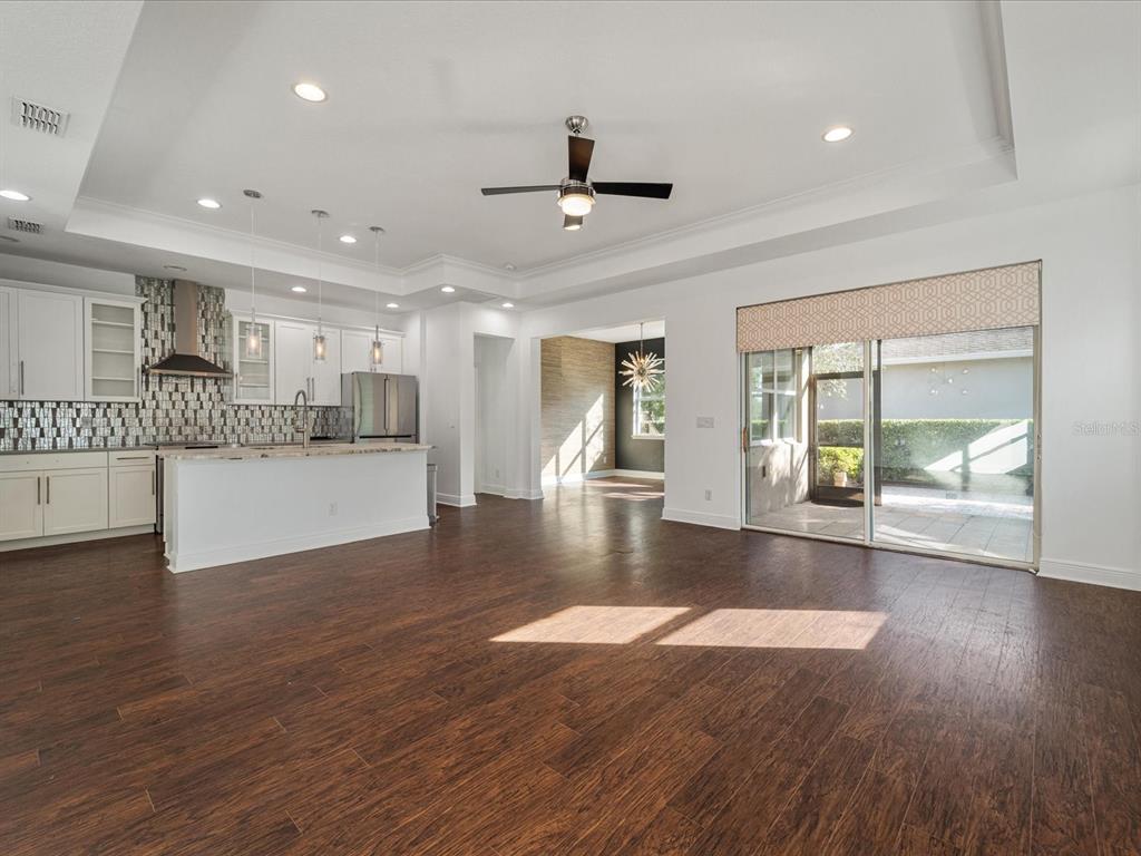 A bright open-concept kitchen and living area featuring dark wood floors and sliding glass doors — 805 MOLLY, SARASOTA, FL