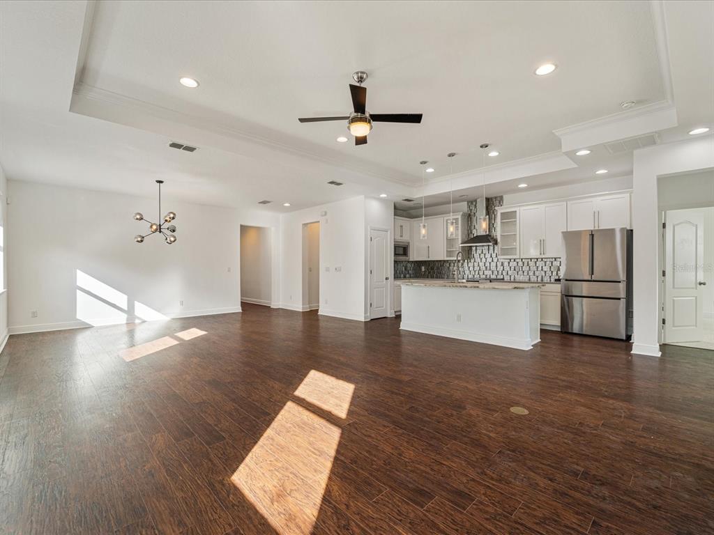 An open-concept kitchen and living area with dark wood floors, white cabinetry, and recessed lighting — 805 MOLLY, SARASOTA, FL