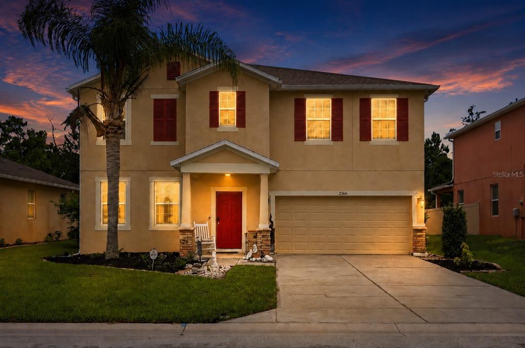 A two-story suburban house with a red front door, tan stucco exterior, and attached garage — 2366 SEQUOIA WAY, DAVENPORT, FL