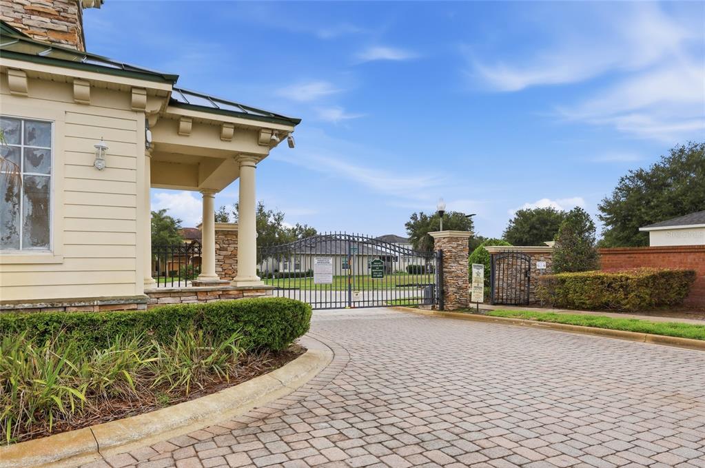 A paved driveway leads to a gated entrance with stone pillars and a guardhouse — 2366 SEQUOIA WAY, DAVENPORT, FL