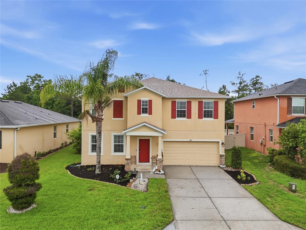 A two-story tan house with a red front door and a two-car garage — 2366 SEQUOIA WAY, DAVENPORT, FL