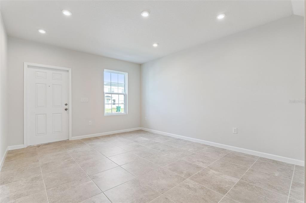 An empty room with light-colored walls, tile flooring, a white door, and a single window — 1206 PORT BLUE WAY, LADY LAKE, FL