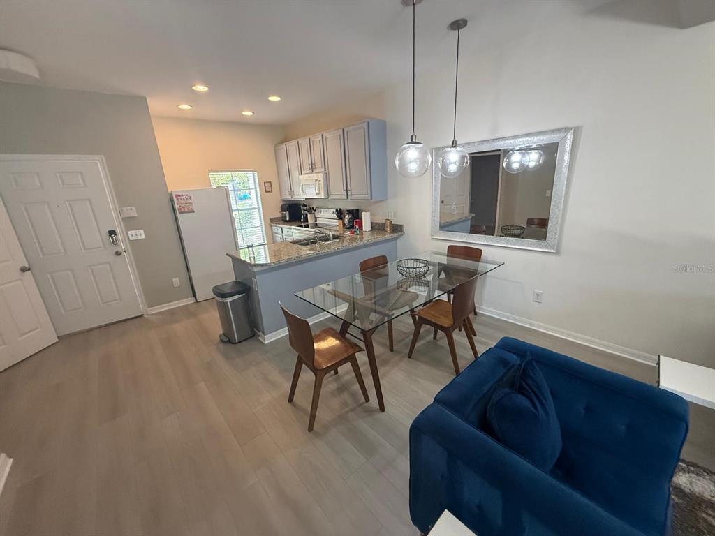 A kitchen with light cabinets and a dining area featuring a glass table and mirror — 4564 ADA LANE, KISSIMMEE, FL