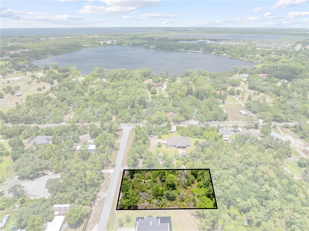 An aerial view shows a rectangular wooded lot outlined in black near a large lake — 0 OESTERLE ROAD, ST CLOUD, FL