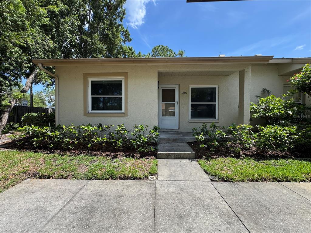 A single-story stucco house with a concrete walkway leading to a white front door — 10853 43RD STREET N UNIT 1201, CLEARWATER, FL