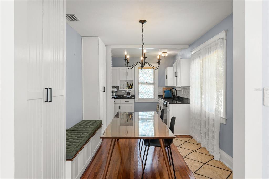 A dining room features a wooden table, a built-in bench with a cushion, and chandelier lighting — 1018 S ELM AVENUE, SANFORD, FL