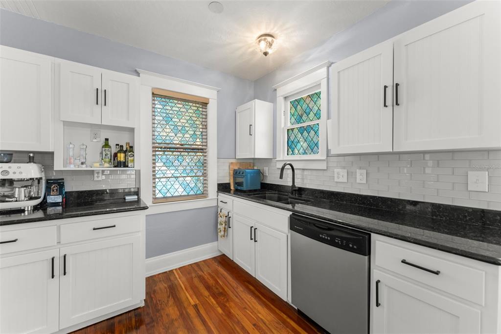 A dining room with a built-in bench, a glass-top table, and white kitchen cabinetry — 1018 S ELM AVENUE, SANFORD, FL