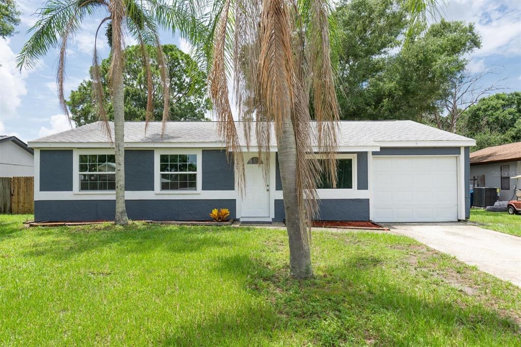 A single-story house with dark gray siding, a white garage door, and palm trees outside — 650 TIMBER BAY CIRCLE W, OLDSMAR, FL
