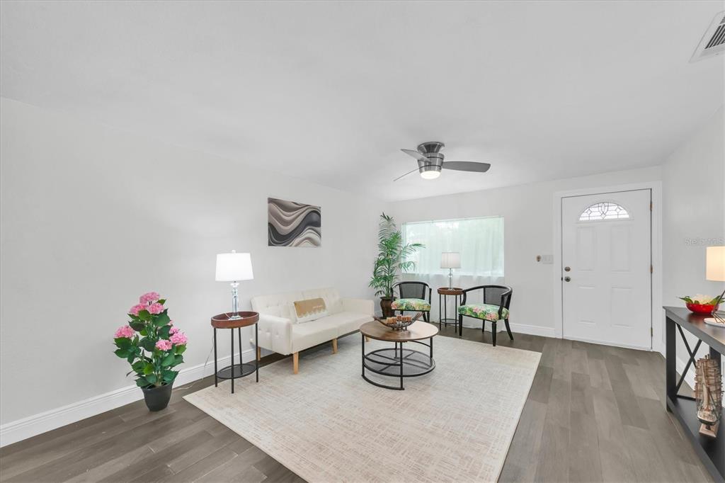 A living room features white walls, dark wood flooring, a sofa, and a ceiling fan — 650 TIMBER BAY CIRCLE W, OLDSMAR, FL