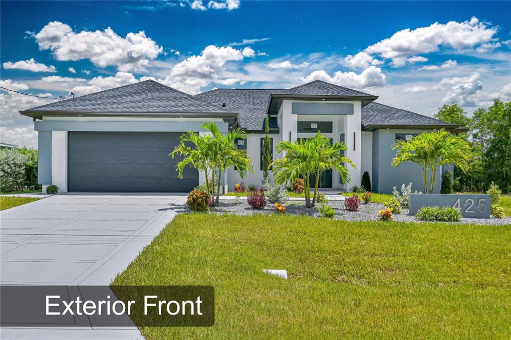 A modern single-story house with a gray garage, white facade, and a landscaped front yard — 425 SW 31ST AVENUE, CAPE CORAL, FL
