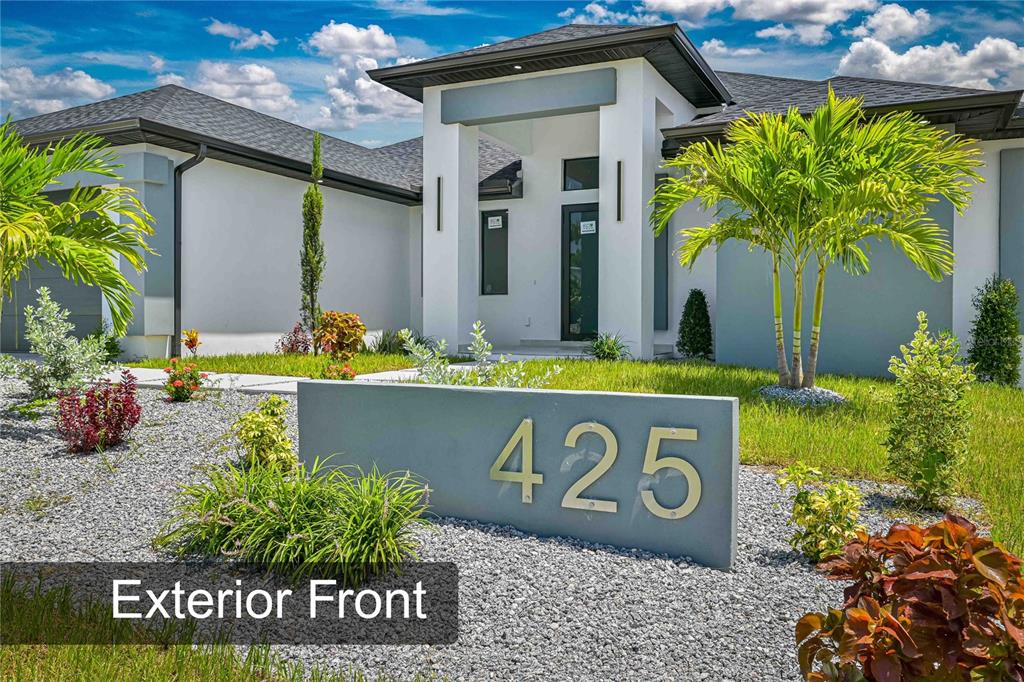 A modern single-story house exterior features a gray address sign in a gravel front yard — 425 SW 31ST AVENUE, CAPE CORAL, FL