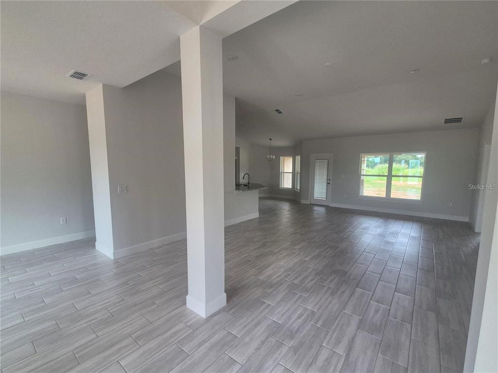 An open-concept living area features light gray wood-look tile flooring and a central support column — 36861 HIDDEN VIEW CIRCLE, DADE CITY, FL